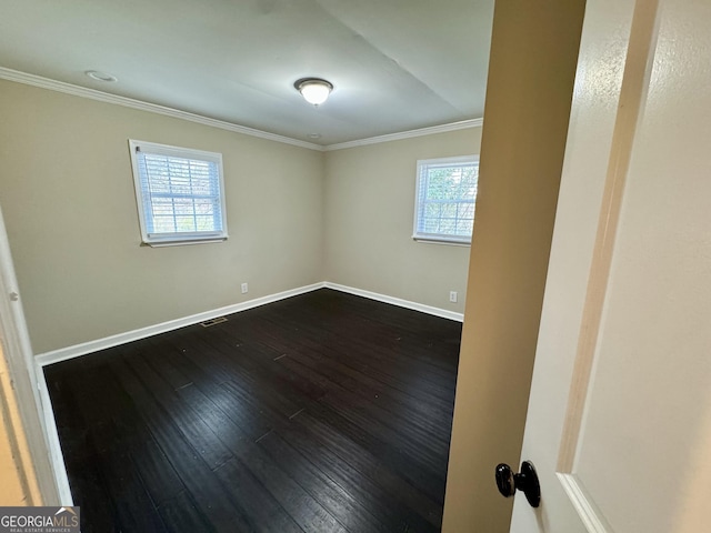 empty room featuring crown molding, dark wood-style floors, baseboards, and visible vents