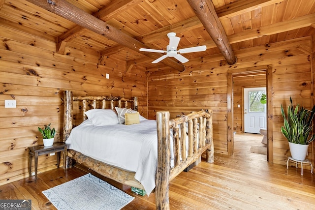 bedroom with wooden ceiling, light wood-style flooring, wooden walls, and beam ceiling