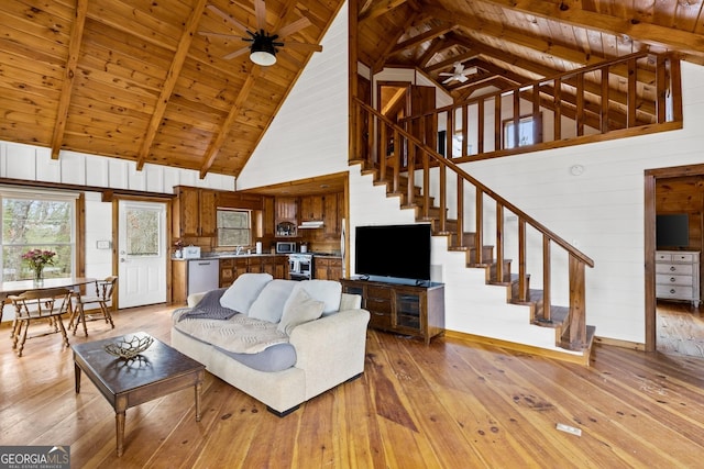 living room with stairway, wooden walls, light wood-style floors, wooden ceiling, and ceiling fan