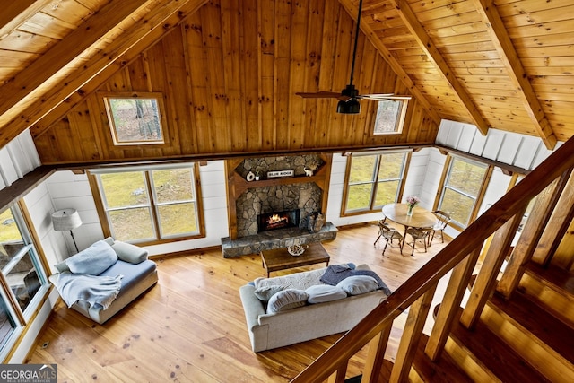 living room with a wealth of natural light, wooden walls, beamed ceiling, and hardwood / wood-style floors