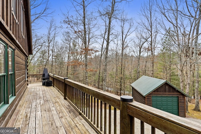 wooden terrace featuring a wooded view, an outdoor structure, and a garage