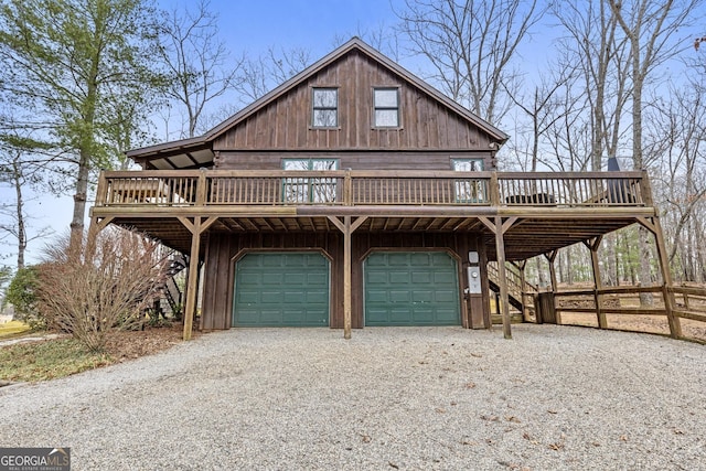 chalet / cabin featuring stairway, an attached garage, a wooden deck, and driveway