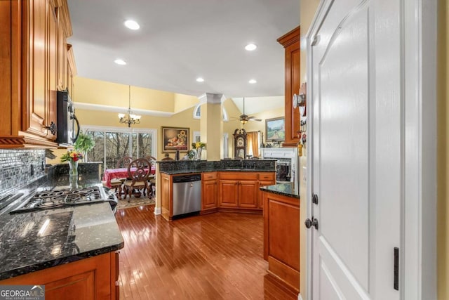 kitchen with brown cabinets, a sink, dark wood-style floors, appliances with stainless steel finishes, and decorative backsplash