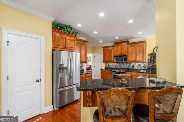 kitchen featuring decorative backsplash, brown cabinetry, a kitchen bar, and stainless steel appliances