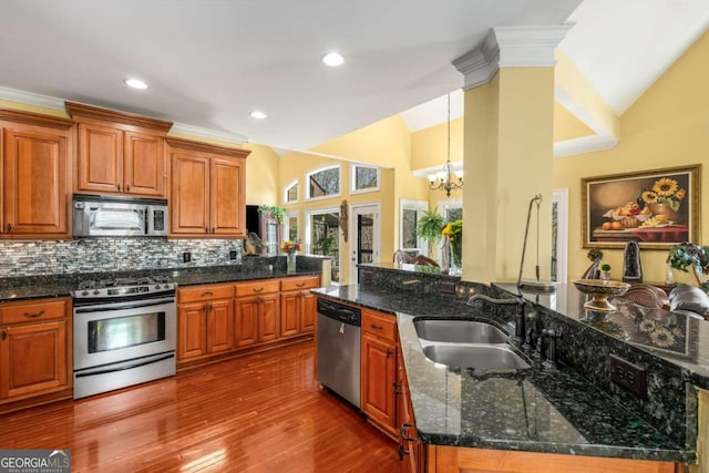 kitchen featuring vaulted ceiling, decorative backsplash, a notable chandelier, stainless steel appliances, and a sink