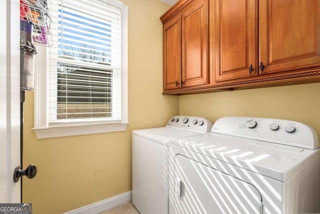 clothes washing area featuring baseboards, cabinet space, and washing machine and clothes dryer