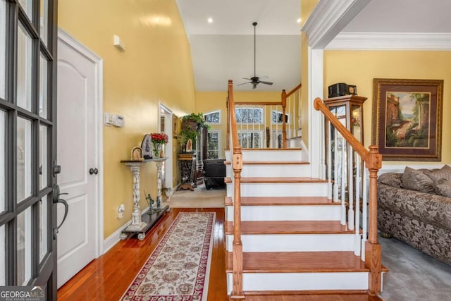stairway with baseboards, crown molding, a ceiling fan, and wood finished floors