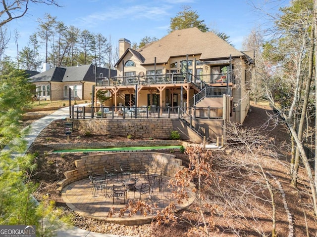 back of property with stairway, a patio, a wooden deck, and a chimney