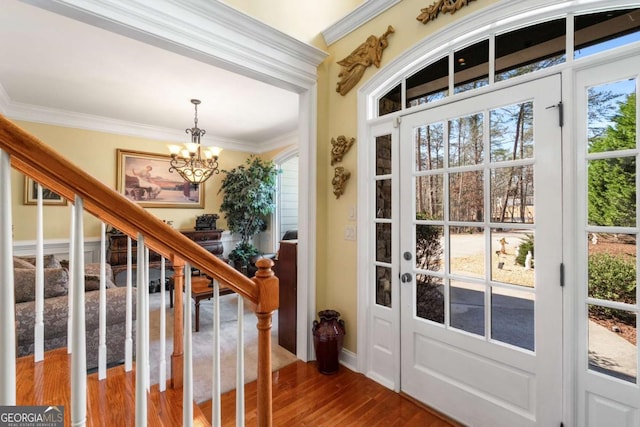 foyer entrance with stairs, a notable chandelier, wood finished floors, and ornamental molding