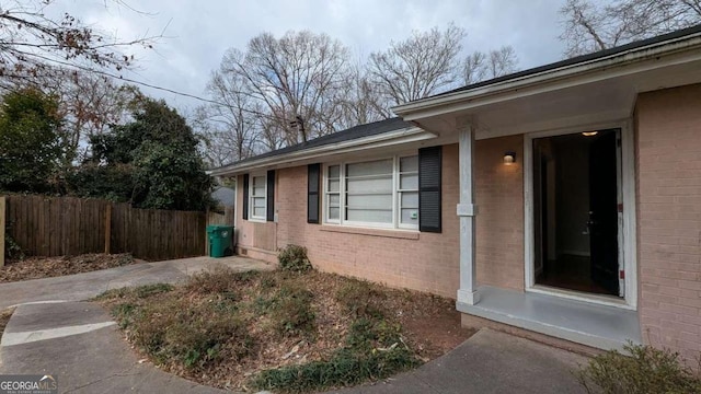 view of side of property featuring fence and brick siding