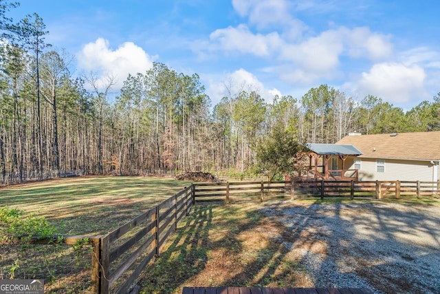 view of yard with a wooded view and fence