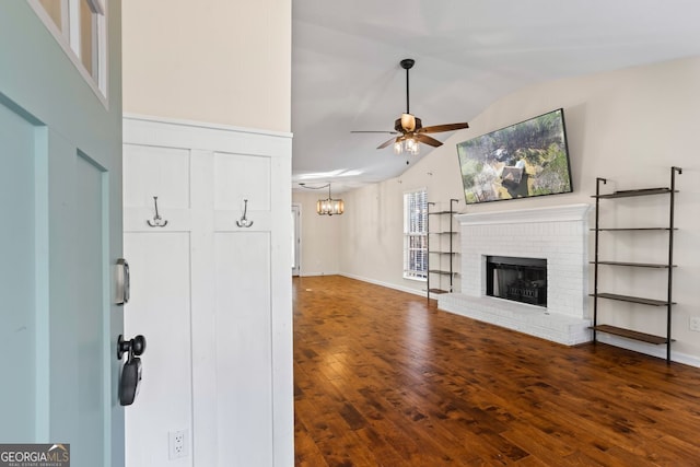 unfurnished living room featuring lofted ceiling, a ceiling fan, wood finished floors, baseboards, and a brick fireplace