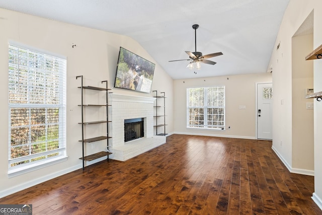 unfurnished living room with baseboards, dark wood-style flooring, ceiling fan, vaulted ceiling, and a brick fireplace