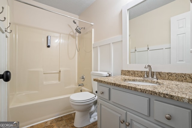 bathroom with toilet, a textured ceiling, wainscoting, a decorative wall, and vanity