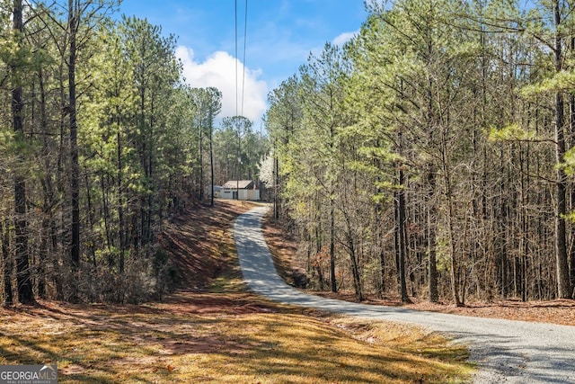 view of street with driveway and a view of trees