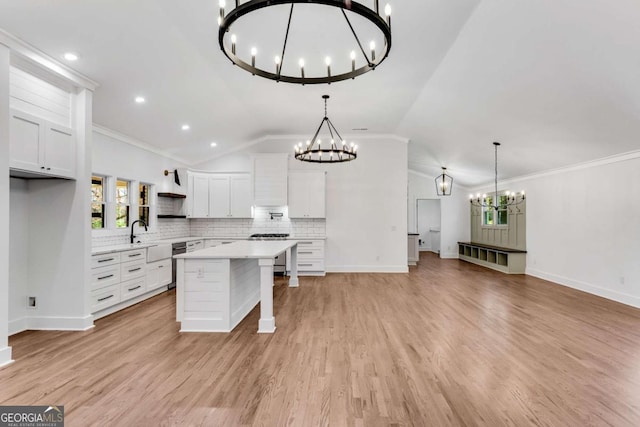 kitchen with open shelves, ventilation hood, light countertops, an inviting chandelier, and a sink