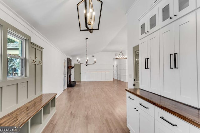 mudroom featuring a brick fireplace, lofted ceiling, an inviting chandelier, and crown molding