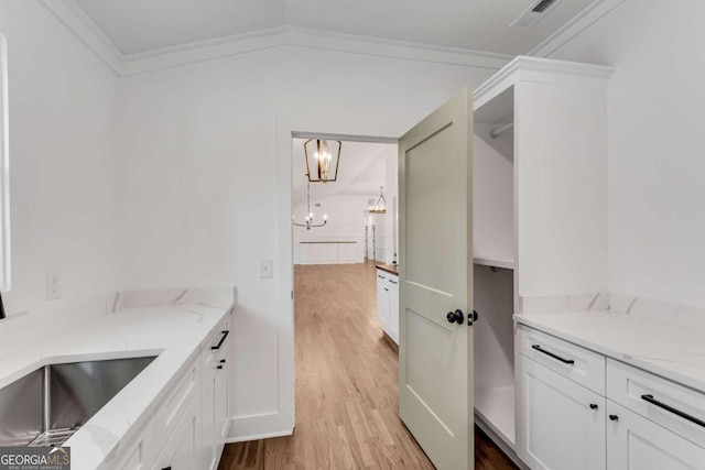 kitchen featuring light stone counters, a notable chandelier, visible vents, and light wood-type flooring