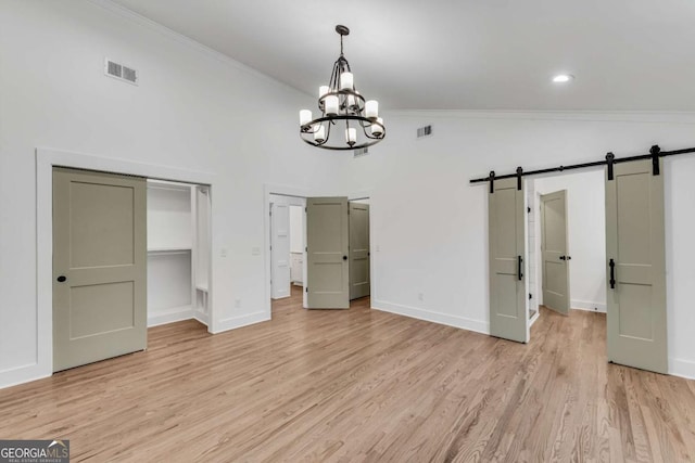 unfurnished bedroom featuring visible vents, lofted ceiling, ornamental molding, and a barn door