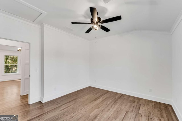 unfurnished room with wood finished floors, baseboards, attic access, ceiling fan, and ornamental molding