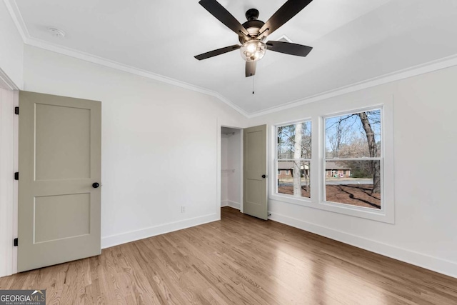 interior space featuring crown molding, ceiling fan, baseboards, vaulted ceiling, and light wood-style floors