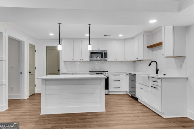 kitchen featuring a sink, stainless steel appliances, light wood-style floors, and white cabinets