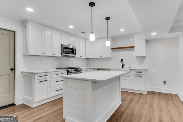 kitchen featuring backsplash, light wood-type flooring, light countertops, stainless steel appliances, and white cabinetry