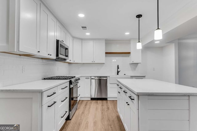 kitchen featuring visible vents, light wood-style flooring, a sink, appliances with stainless steel finishes, and white cabinetry