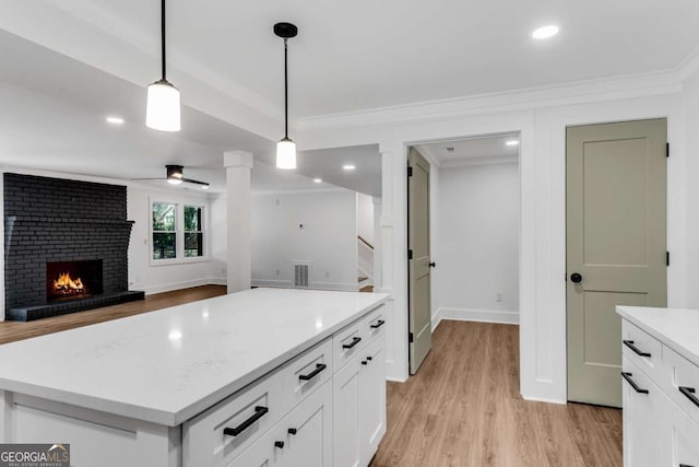 kitchen featuring visible vents, ornamental molding, white cabinets, light countertops, and a brick fireplace