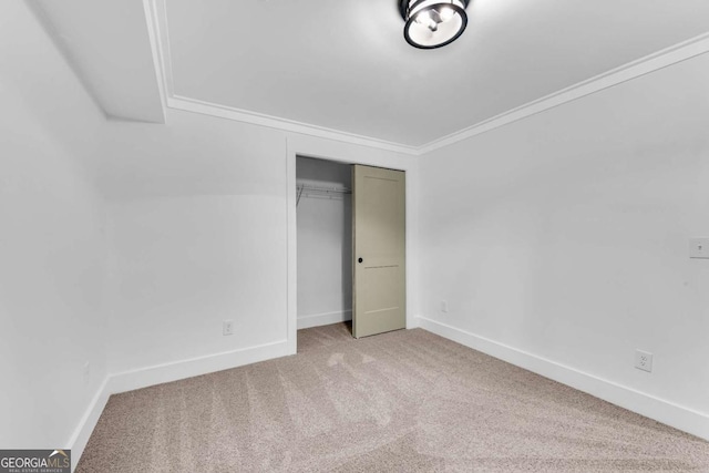 unfurnished bedroom featuring crown molding, carpet, baseboards, and a closet