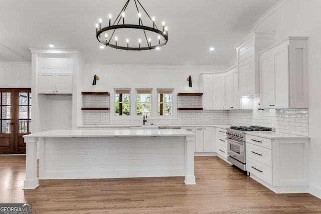 kitchen with open shelves, ornamental molding, stainless steel range, light countertops, and a center island