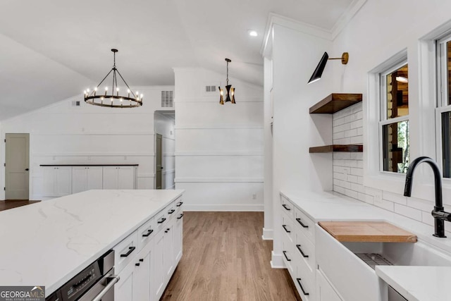 kitchen featuring tasteful backsplash, open shelves, vaulted ceiling, white cabinets, and a sink