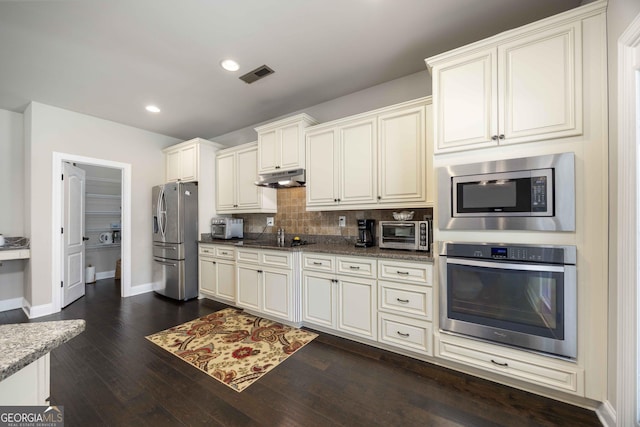 kitchen with visible vents, dark wood-type flooring, under cabinet range hood, tasteful backsplash, and appliances with stainless steel finishes