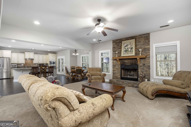 living room with dark wood-style floors, visible vents, a ceiling fan, recessed lighting, and a stone fireplace