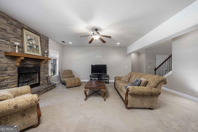 living room with stairs, baseboards, a stone fireplace, and carpet flooring