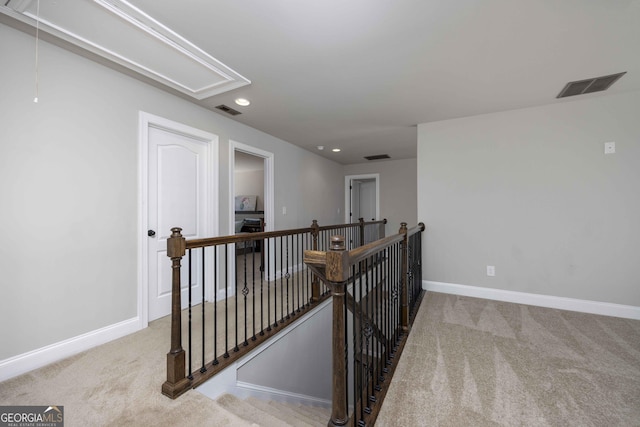 hall with carpet, attic access, an upstairs landing, and visible vents