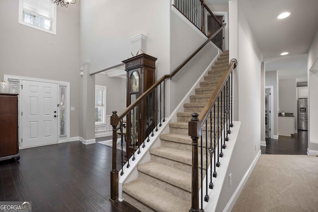 entryway with dark wood-type flooring, recessed lighting, baseboards, a towering ceiling, and stairs