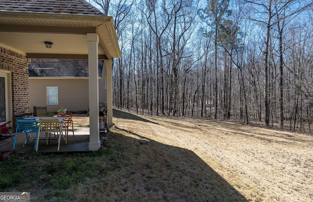 view of yard featuring a patio area and a forest view