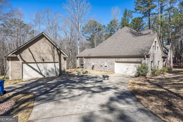 view of side of home with a garage, brick siding, and roof with shingles