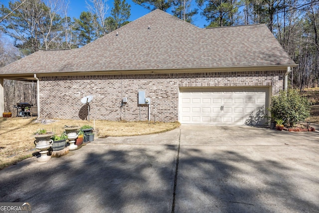 view of home's exterior featuring concrete driveway, an attached garage, brick siding, and a shingled roof