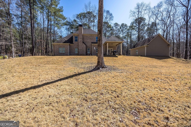 view of front of property featuring a front yard, brick siding, and a chimney