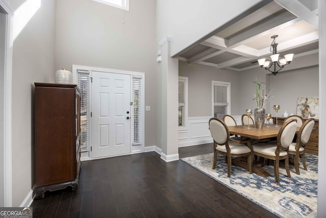 dining space with baseboards, coffered ceiling, dark wood finished floors, beamed ceiling, and a chandelier