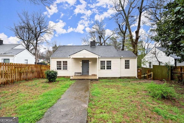 bungalow-style house featuring a front lawn, roof with shingles, fence private yard, and a chimney