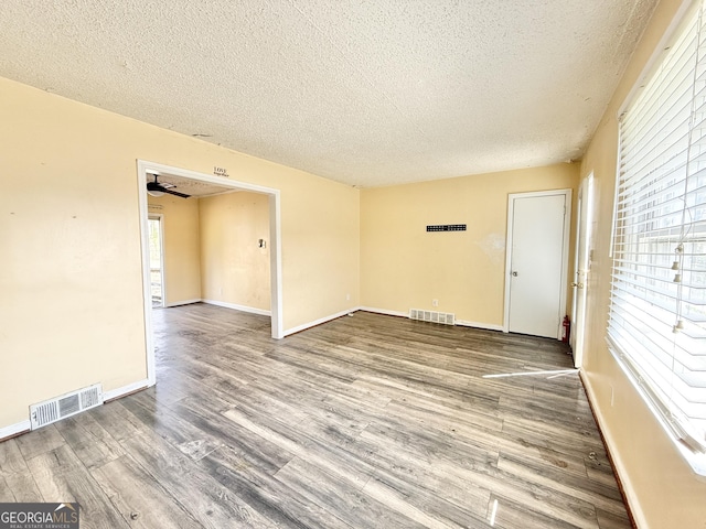 empty room featuring plenty of natural light, wood finished floors, and visible vents