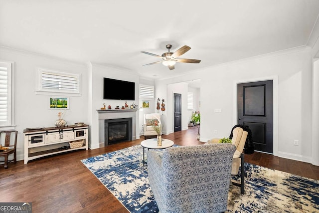 living room with a wealth of natural light, wood finished floors, a glass covered fireplace, and ornamental molding