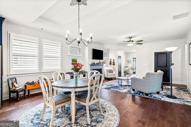 dining room with visible vents, baseboards, a fireplace, hardwood / wood-style flooring, and crown molding