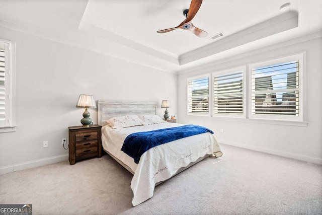 carpeted bedroom with a tray ceiling, baseboards, and visible vents