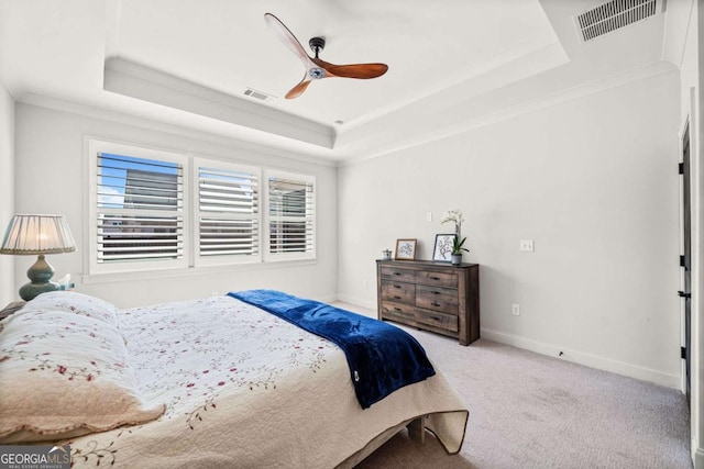 carpeted bedroom with a tray ceiling, baseboards, visible vents, and ornamental molding