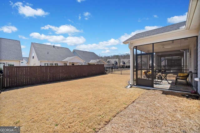 view of yard featuring a residential view, a patio, a fenced backyard, and a sunroom