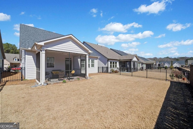 rear view of property with a residential view, roof with shingles, a fenced backyard, and a sunroom